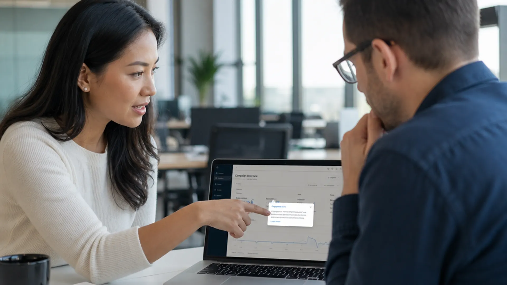 Product manager explaining in-app tooltip to a colleague in an office.